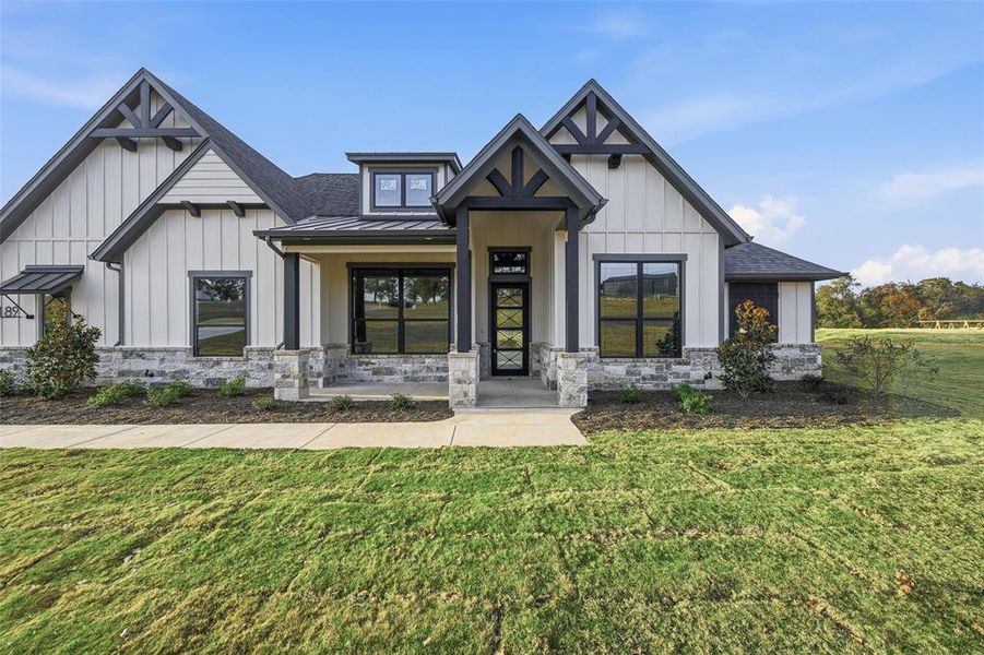 Modern inspired farmhouse with a standing seam roof, a front yard, and board and batten siding Modern inspired farmhouse with a standing seam roof, a front yard, and board and batten siding