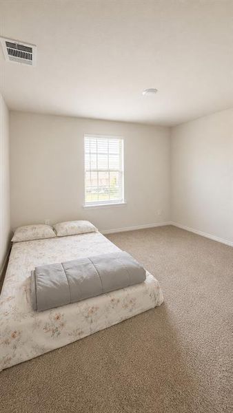 Carpeted room featuring a window with blinds, a ceiling-mounted light fixture, and a white ceiling with a visible vent Carpeted room featuring a window with blinds, a ceiling-mounted light fixture, and a white ceiling with a visible vent