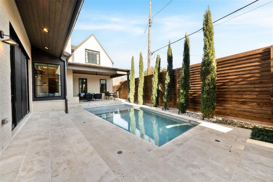 View of swimming pool with patio surround and a fenced backyard