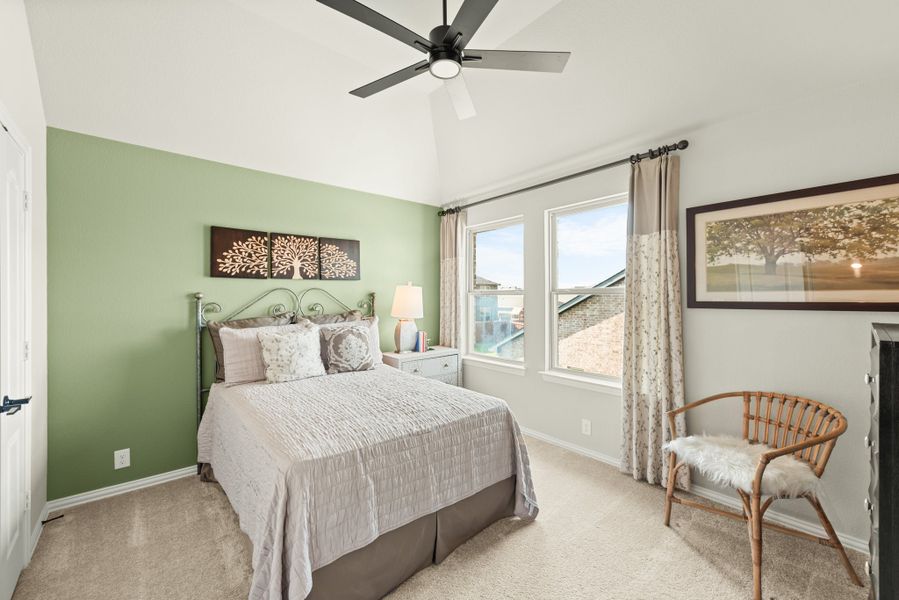 Bedroom with green accent wall, vaulted ceiling, ceiling fan, and carpet flooring