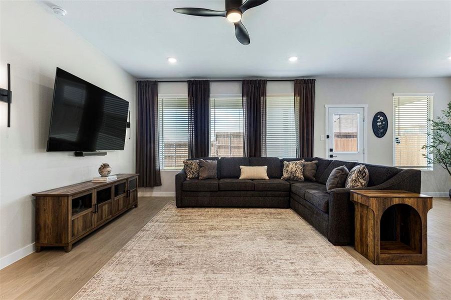 Spacious living area featuring wood-finish flooring, recessed lighting, and a modern ceiling fan Spacious living area featuring wood-finish flooring, recessed lighting, and a modern ceiling fan