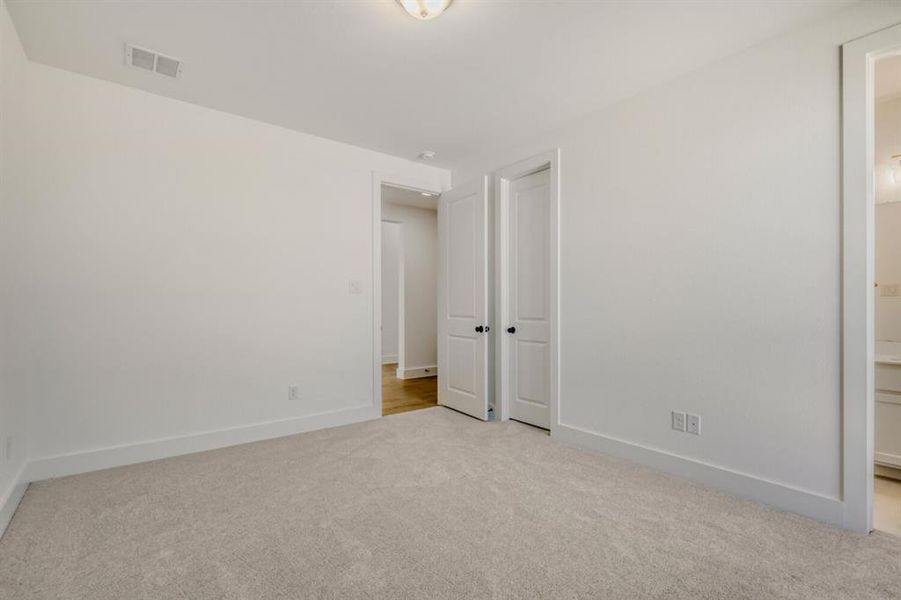 Unfurnished bedroom featuring light colored carpet and ensuite bath