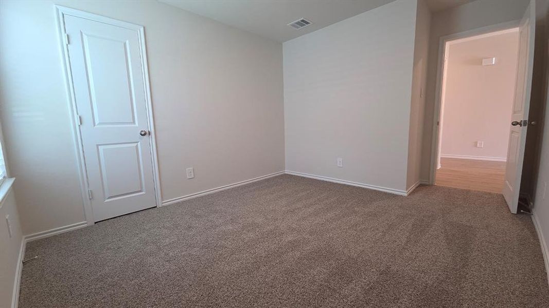 Carpeted interior room featuring light gray wall paint, white trim, and a paneled door