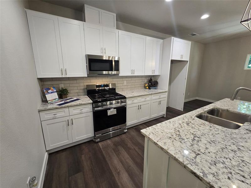 Kitchen featuring white cabinets, appliances with stainless steel finishes, dark hardwood / wood-style floors, and sink