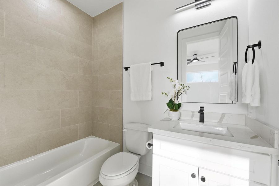 Clean, modern bathroom featuring a tiled tub-and-shower combination, sleek white vanity with quartz countertop, contemporary fixtures, and a bright, polished design.