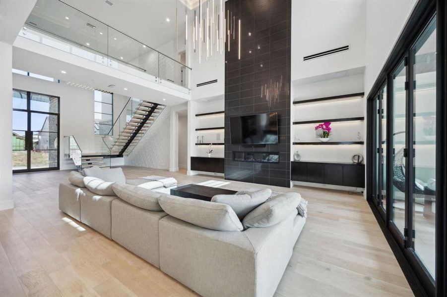 Living room with light hardwood / wood-style floors and a towering ceiling