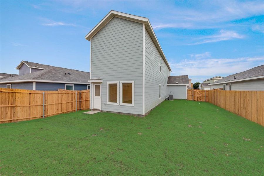 Rear view of property with cooling unit and a lawn