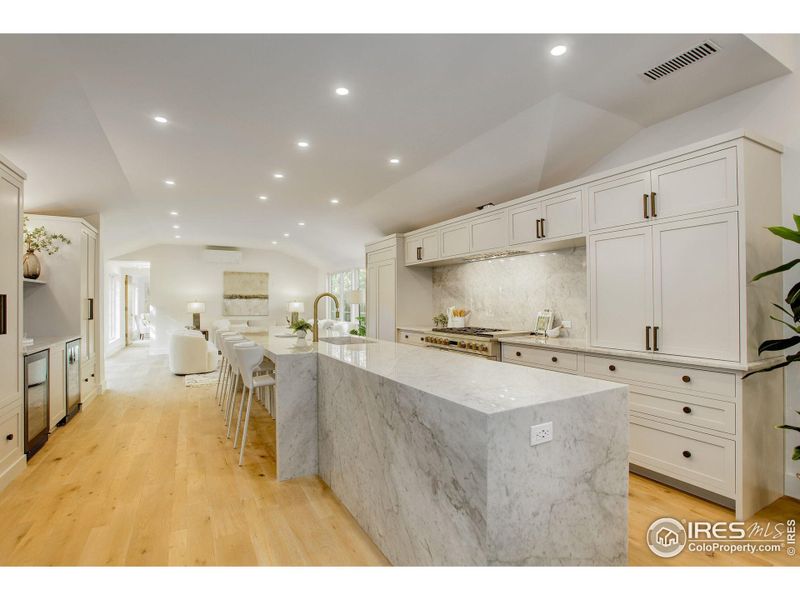 The heart of this home, the chef's kitchen, features an 17ft White Carrara Marble island with waterfall edges and top-of-the-line Monogram appliances.