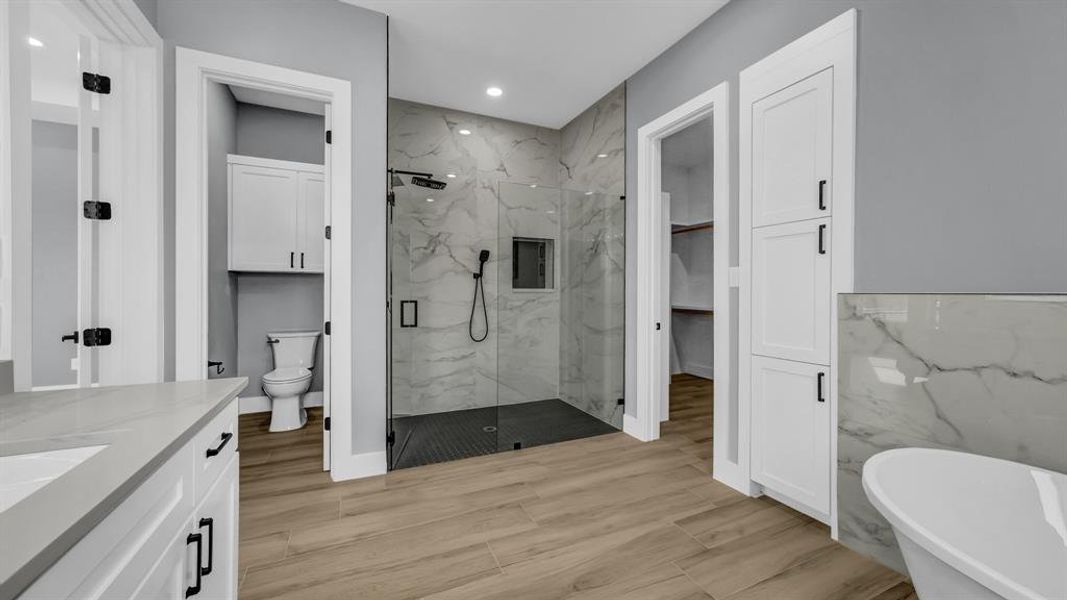 Bathroom with a freestanding bath, a marble finish shower, recessed lighting, vanity, and wood finish floors
