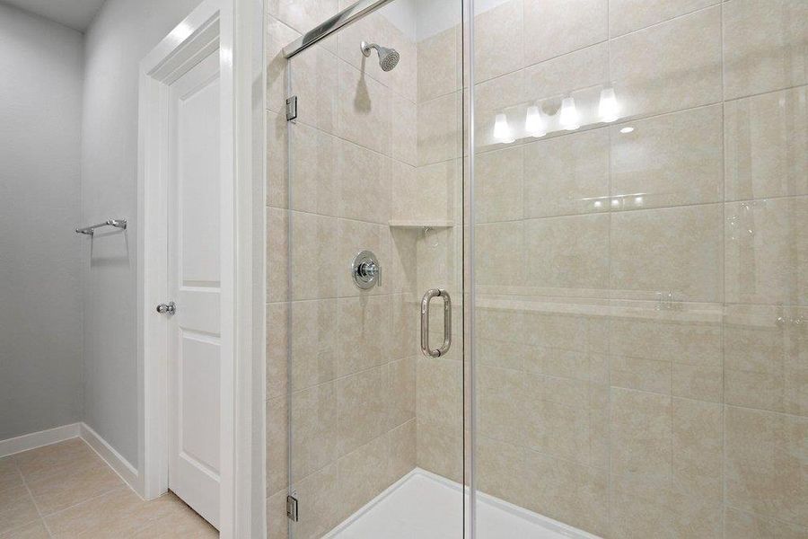 Full bath featuring a shower stall and light tile patterned floors