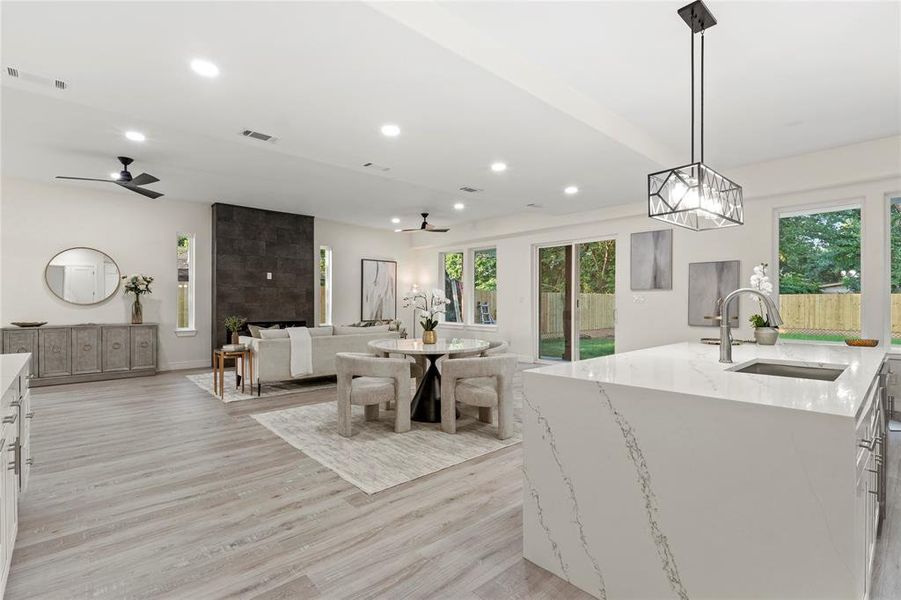 Kitchen with recessed lighting, open floor plan, light wood-type flooring, light stone counters, and a ceiling fan Kitchen with recessed lighting, open floor plan, light wood-type flooring, light stone counters, and a ceiling fan