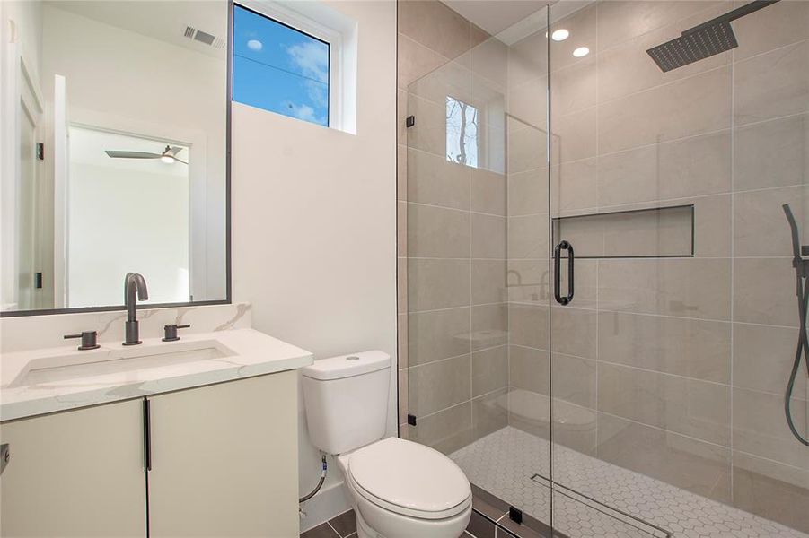 Bathroom with vanity, a shower with door, ceiling fan, tile patterned flooring, and toilet