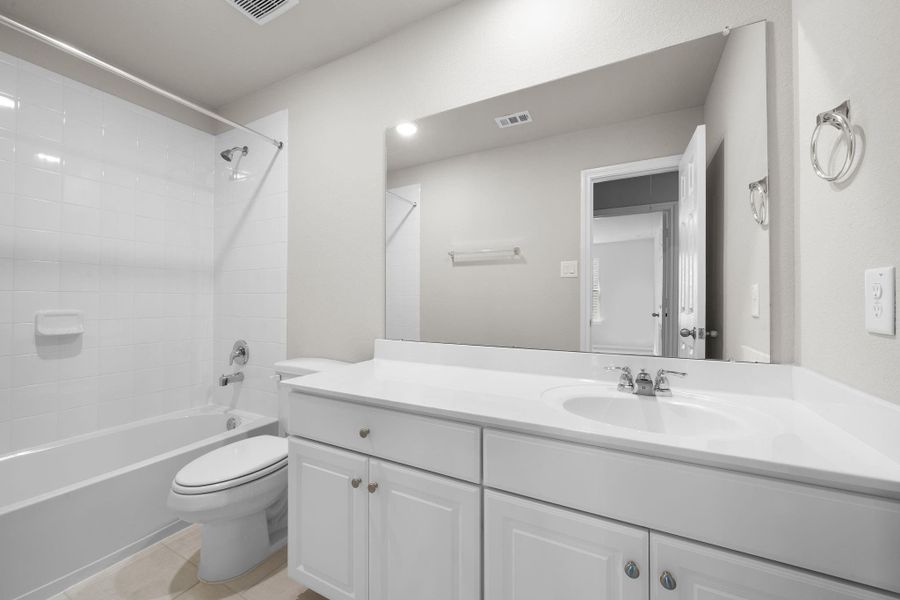 The secondary bath features tile flooring, white cabinetry and light countertops and a shower/tub combo. Perfect for accommodating any visiting family and friends.