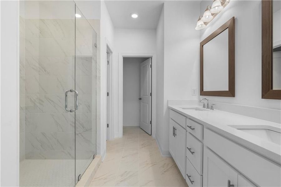 primary bathroom with frameless shower door and double sinks with framed mirrors - *Pictures represent a previously built home, not the actual home, home is under construction*