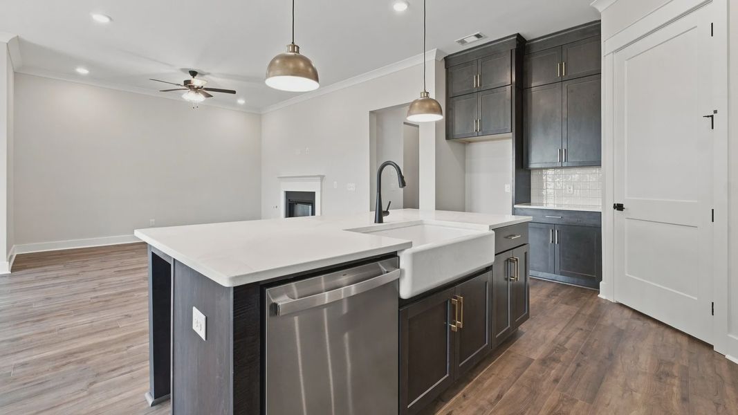 Kitchen island featuring quartz countertops with dishwasher and sink in the middle of spacious dining space.