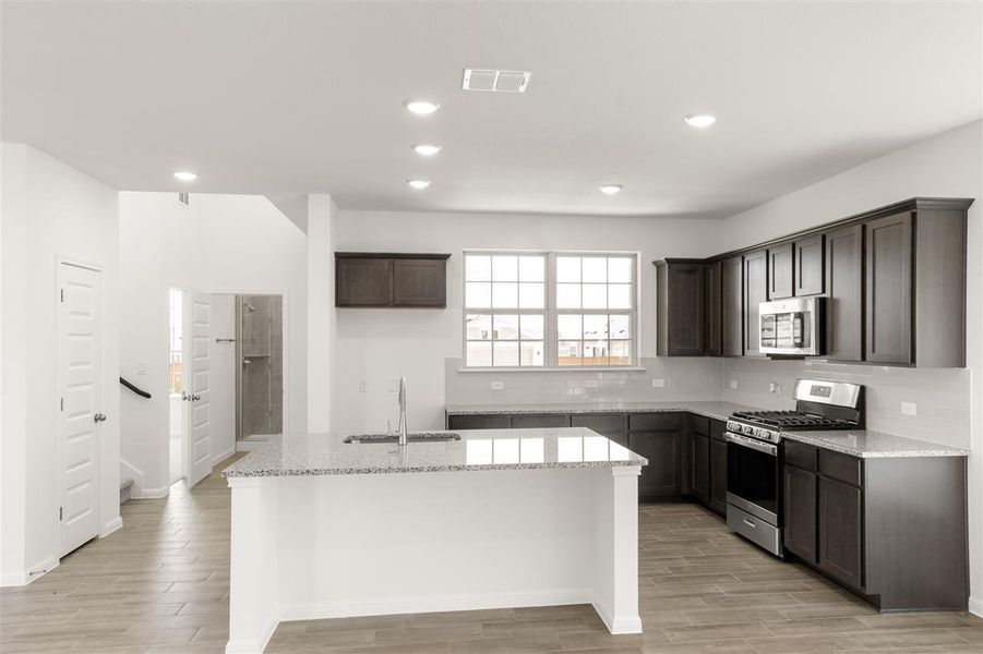 Kitchen featuring dark brown cabinets, a sink, stainless steel appliances, and visible vents