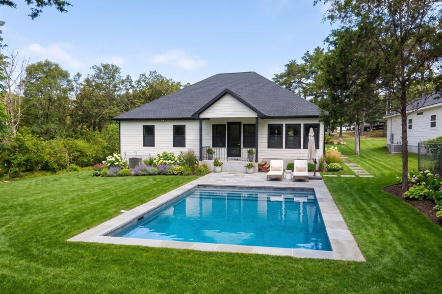 Virtual Staging. Just a possibility. An inviting backyard oasis features a glistening inground pool surrounded by ample green lawn and mature landscaping.