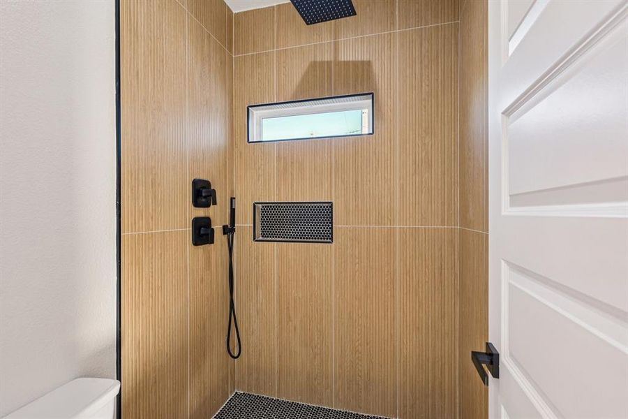 Full bathroom featuring a tile shower and toilet