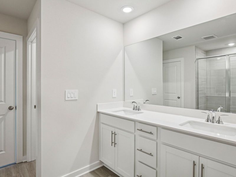 The primary bathroom offers dual vanity sinks and a walk-in shower.