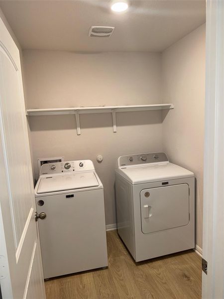 Dedicated laundry area featuring wood-finish flooring, a white shelving unit, and recessed lighting Dedicated laundry area featuring wood-finish flooring, a white shelving unit, and recessed lighting