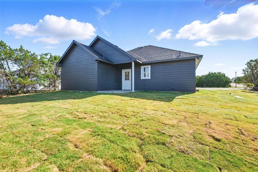 Back of property with a yard and roof with shingles Back of property with a yard and roof with shingles