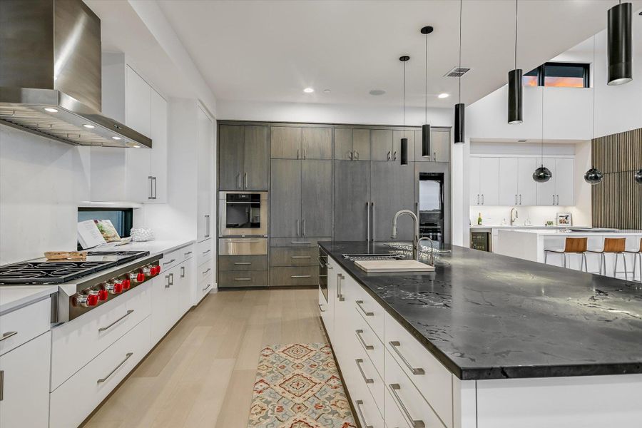 Kitchen featuring two tone cabinetry, modern cabinets, decorative light fixtures, stainless steel appliances, and light wood-style flooring Kitchen featuring two tone cabinetry, modern cabinets, decorative light fixtures, stainless steel appliances, and light wood-style flooring