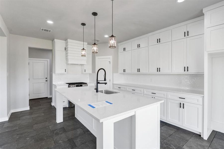 Kitchen with a sink, recessed lighting, light countertops, white cabinets, and a kitchen island with sink