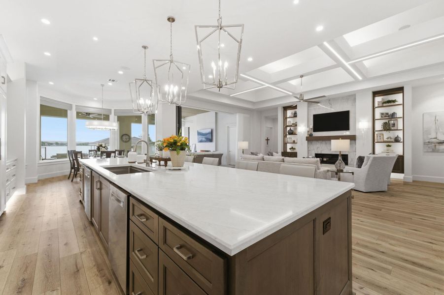 Kitchen featuring dark wood finish cabinets, a ceiling fan, a fireplace, a spacious island, and light wood finished floors
