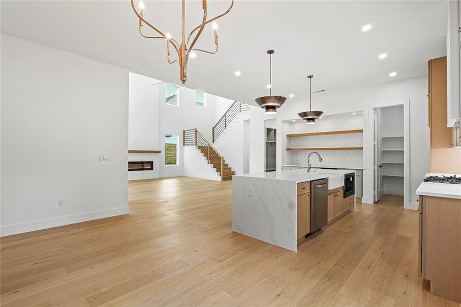 Kitchen with light stone countertops, open floor plan, hanging light fixtures, light wood-style flooring, and recessed lighting
