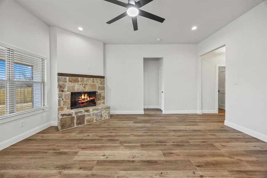 Unfurnished living room featuring light wood-style flooring, ceiling fan, a fireplace, and recessed lighting Unfurnished living room featuring light wood-style flooring, ceiling fan, a fireplace, and recessed lighting