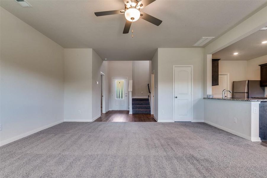 Unfurnished living room featuring dark colored carpet, ceiling fan, and recessed lighting