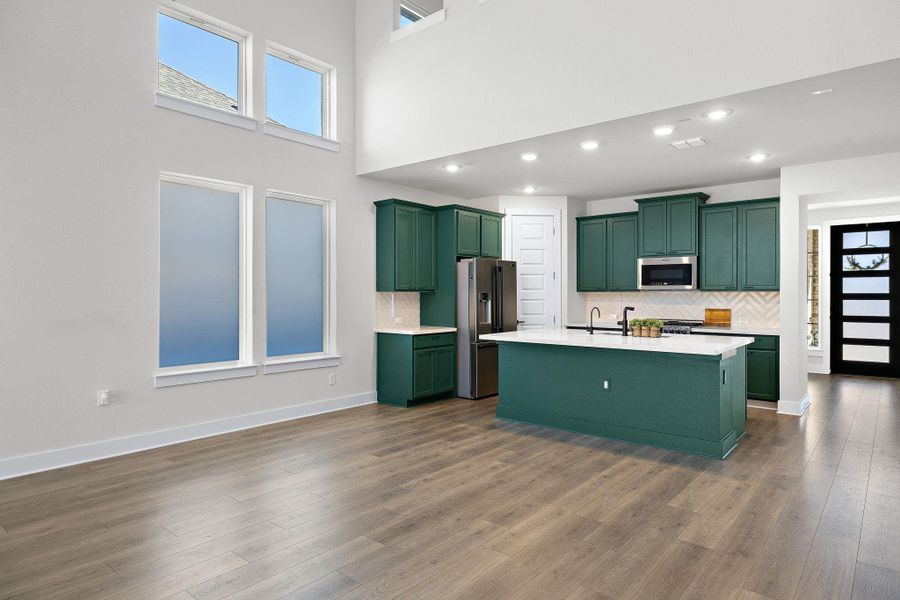 Kitchen featuring green cabinets, a center island with sink, stainless steel appliances, and reverse osmosis water filtration.