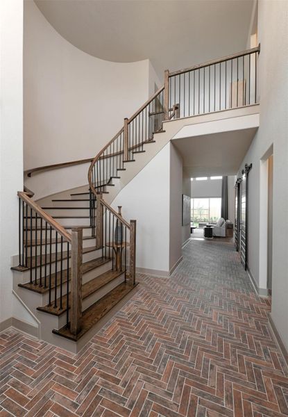 Welcoming entryway features elegant brick paver flooring and soaring high ceilings that create a bright and inviting first impression.