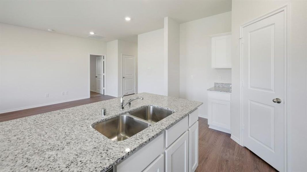 Kitchen featuring white cabinetry, dark wood finished floors, light stone countertops, and recessed lighting Kitchen featuring white cabinetry, dark wood finished floors, light stone countertops, and recessed lighting