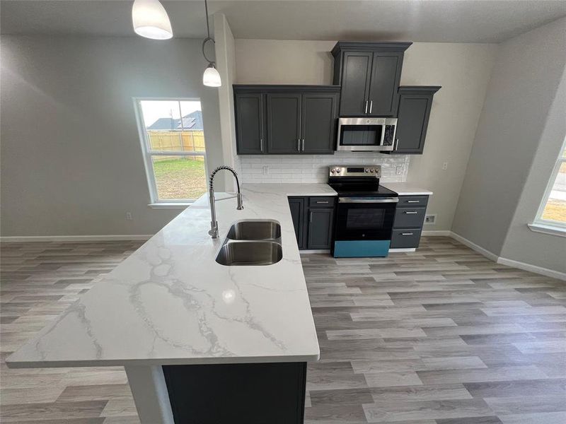 Kitchen featuring plenty of natural light, sink, stainless steel appliances, and decorative light fixtures