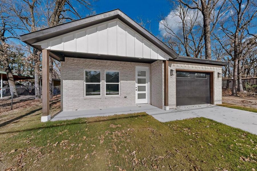View of front facade with board and batten siding, concrete driveway, a front lawn, an attached garage, and a porch