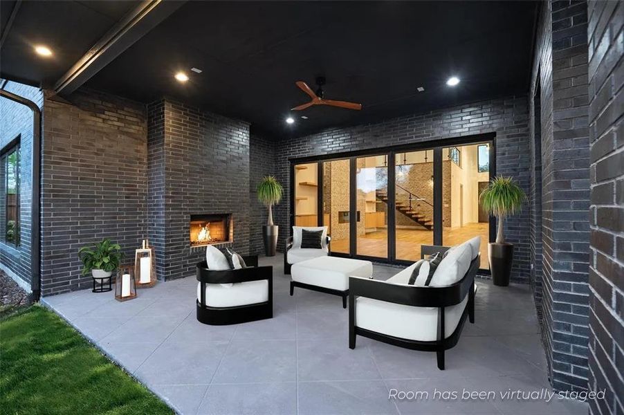 Covered outdoor patio featuring a gray brick fireplace, recessed lighting, and a ceiling fan Covered outdoor patio featuring a gray brick fireplace, recessed lighting, and a ceiling fan