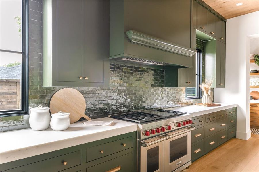 Kitchen featuring green cabinetry, double oven range, light countertops, and light wood-style floors