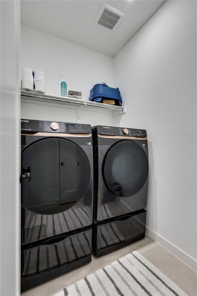 An organized laundry closet features clean walls and modern tile flooring. An organized laundry closet features clean walls and modern tile flooring.