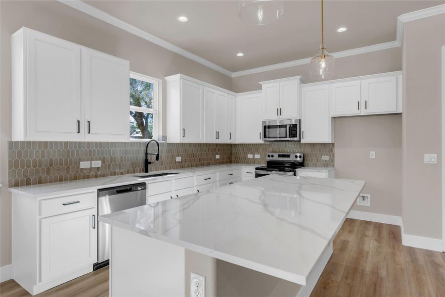 Kitchen with light stone counters, white cabinets, light wood-style flooring, and ornamental molding