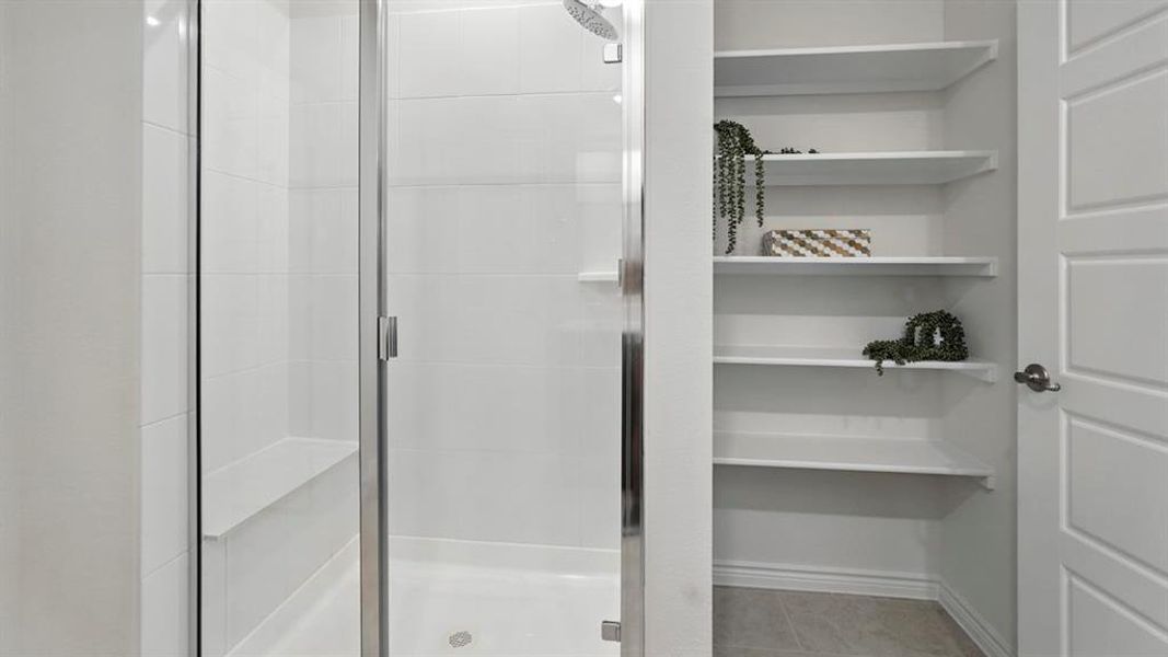 Bathroom with a shower stall, light tile patterned floors, and a closet