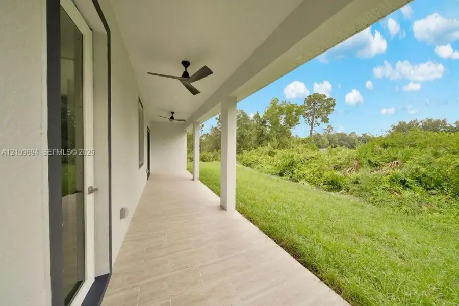Covered lanai featuring tile flooring, structural columns, and mounted ceiling fans