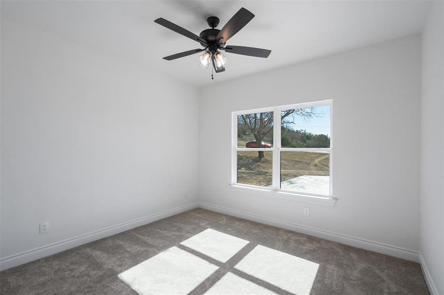 Spare room featuring ceiling fan and dark colored carpet