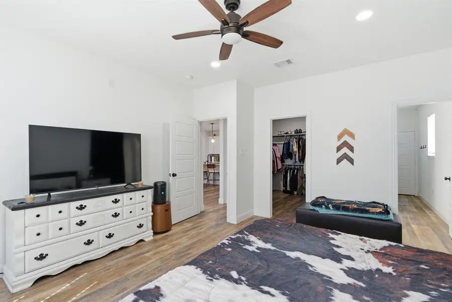 Bedroom with light wood finished floors, a spacious closet, a ceiling fan, and recessed lighting Bedroom with light wood finished floors, a spacious closet, a ceiling fan, and recessed lighting