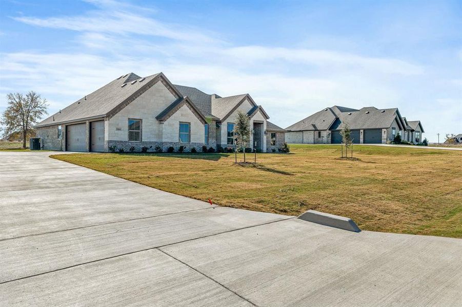 French country inspired facade featuring a front yard, stone siding, and concrete driveway