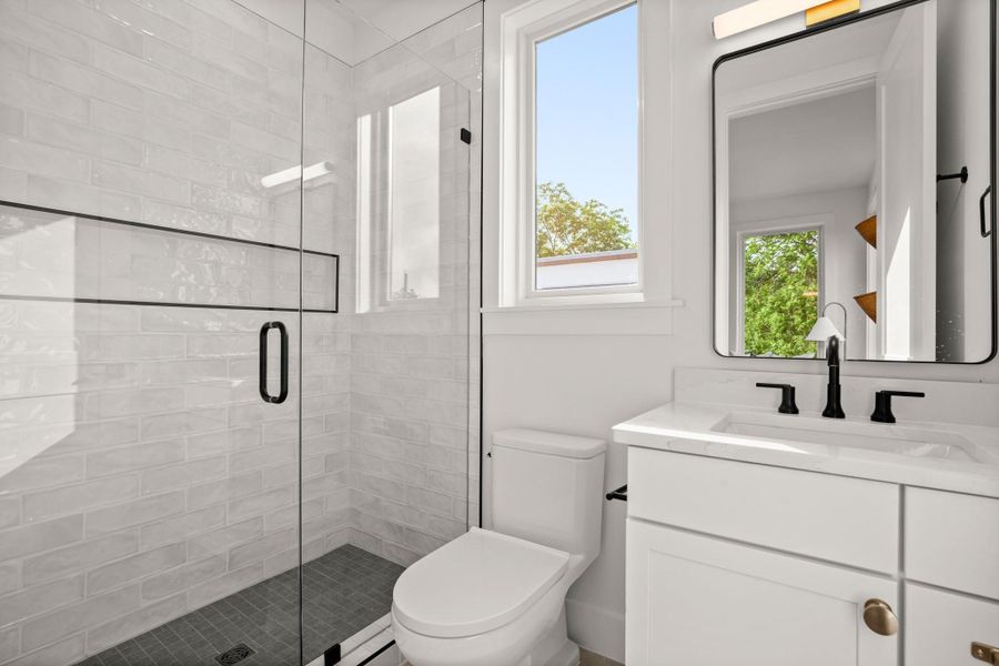 Bathroom featuring toilet, a shower stall, and vanity