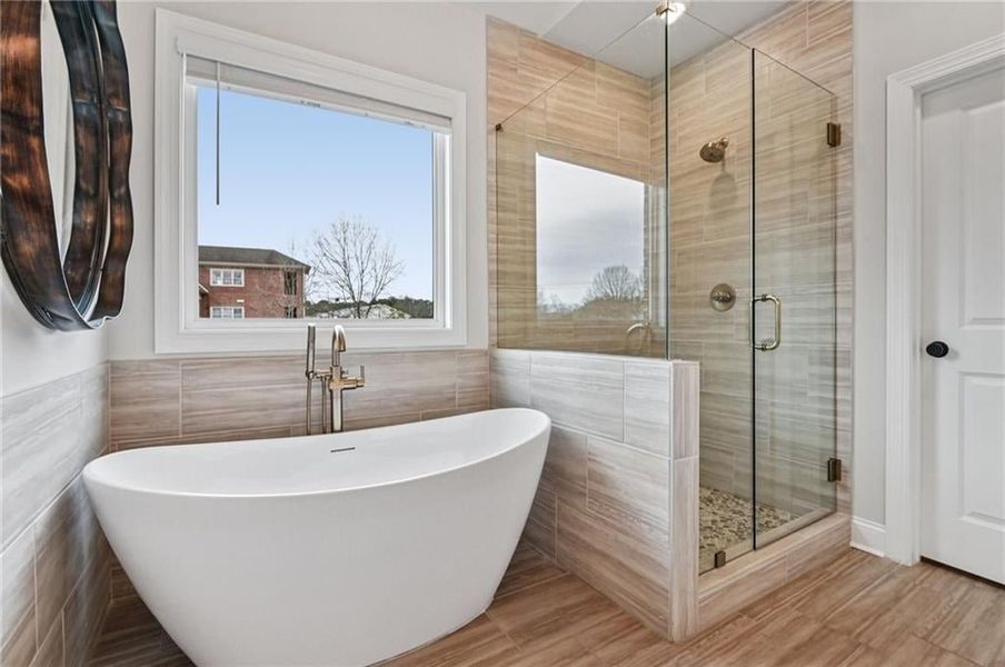 Full bath with a stall shower, a freestanding bath, and tile walls