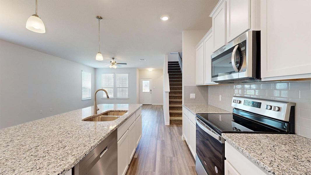 Kitchen featuring stainless steel appliances, white cabinets, and pendant lighting