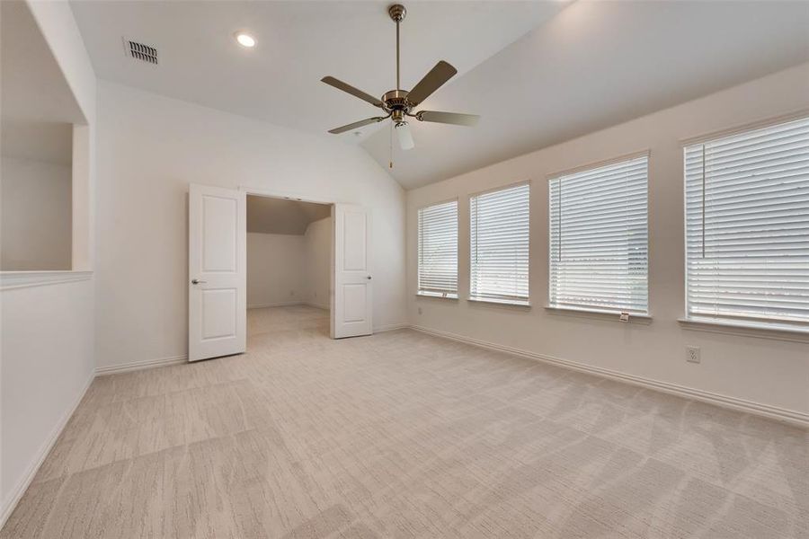 Unfurnished bedroom featuring ceiling fan, light carpet, and lofted ceiling