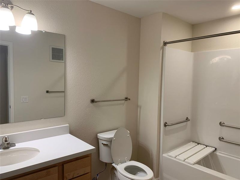 Full bath with a textured wall, vanity, and a shower